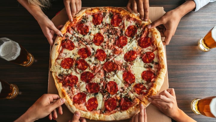 hands reach for slices of a large pepperoni pizza | pizza in Santa Fe