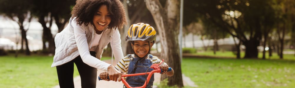 A mother helping her child ride a bike near Cobbs Creek Apartment Homes in Decatur, Georgia