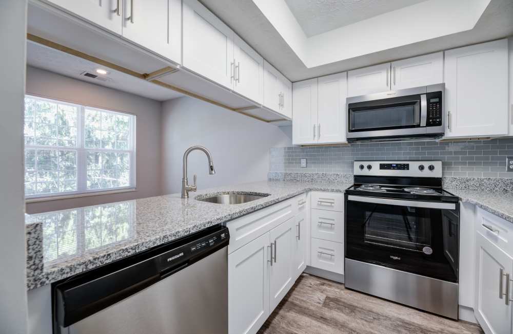renovated kitchen with modern white cabinets, stainless steel appliances, and granite countertops