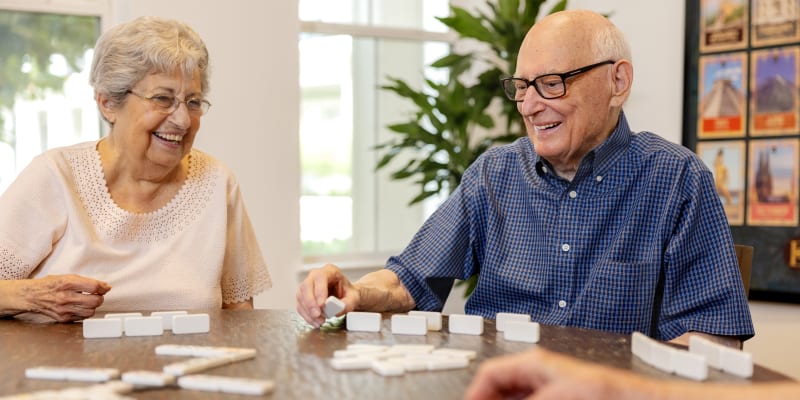 Couple playing dominoes at Glenncrest at Johns Creek memory care in Johns Creek, Georgia