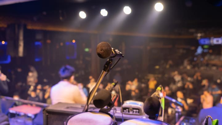 A mic on a stage. A crowd in the background. 