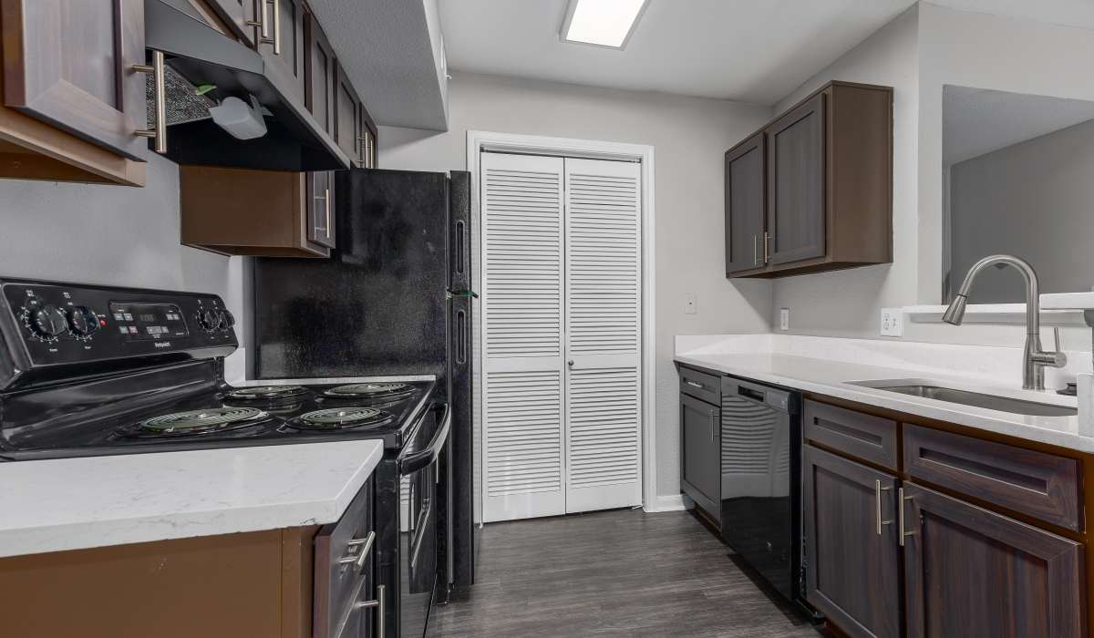 Kitchen with dark wood cabinets and modern appliances at Oaks of Kingwood Apartments in Kingwood, Texas