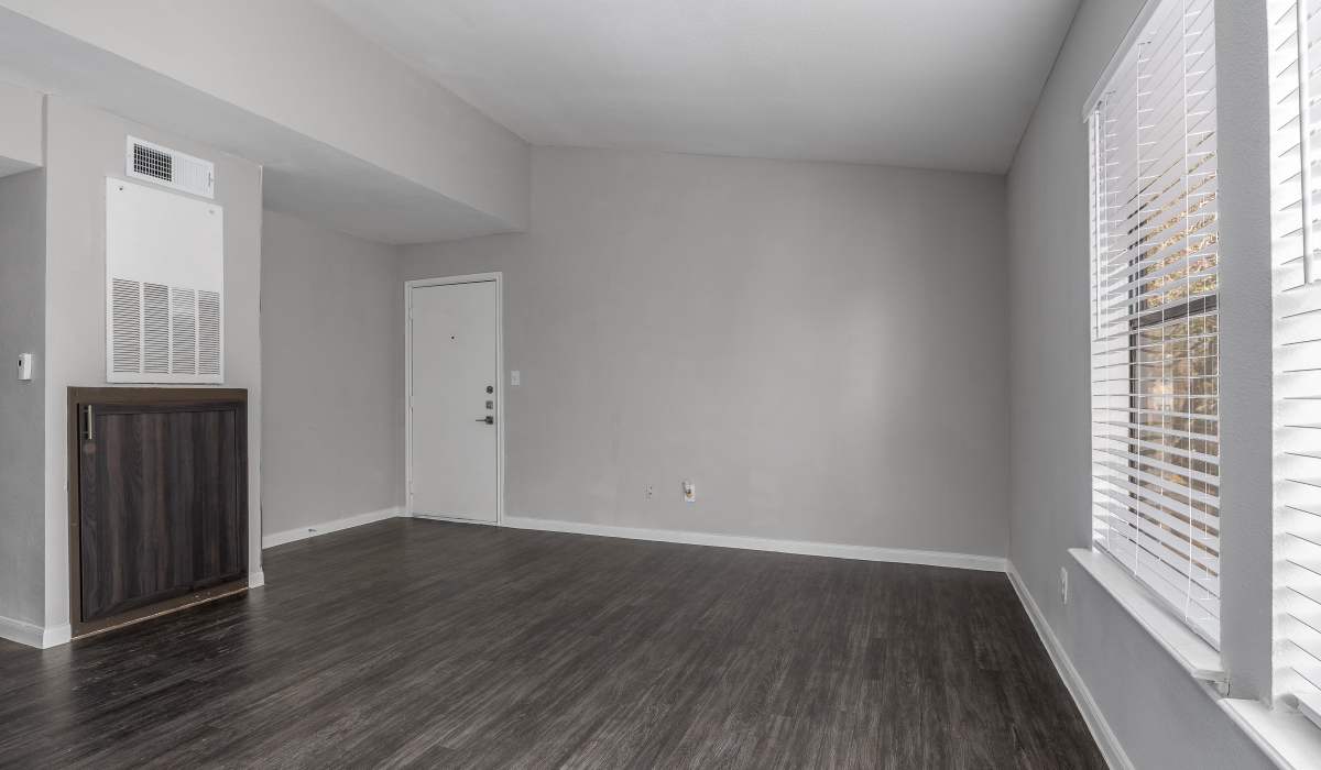 Open apartment living room with wood-style flooring at Oaks of Kingwood Apartments in Kingwood, Texas