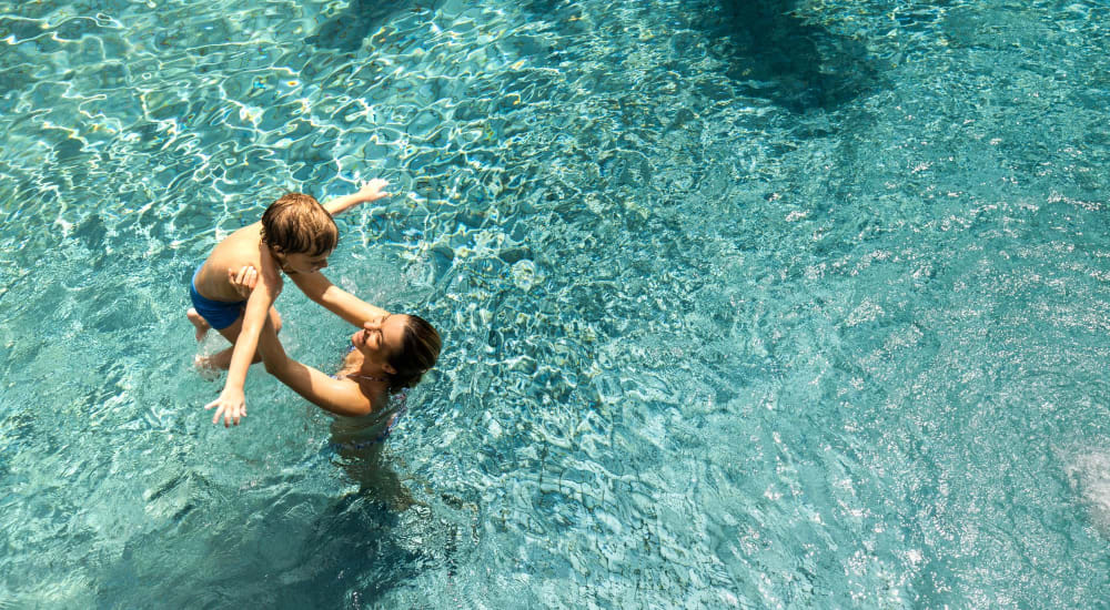 A mother holding up her child in the swimming pool at Falcon Park Apartments in Layton, Utah