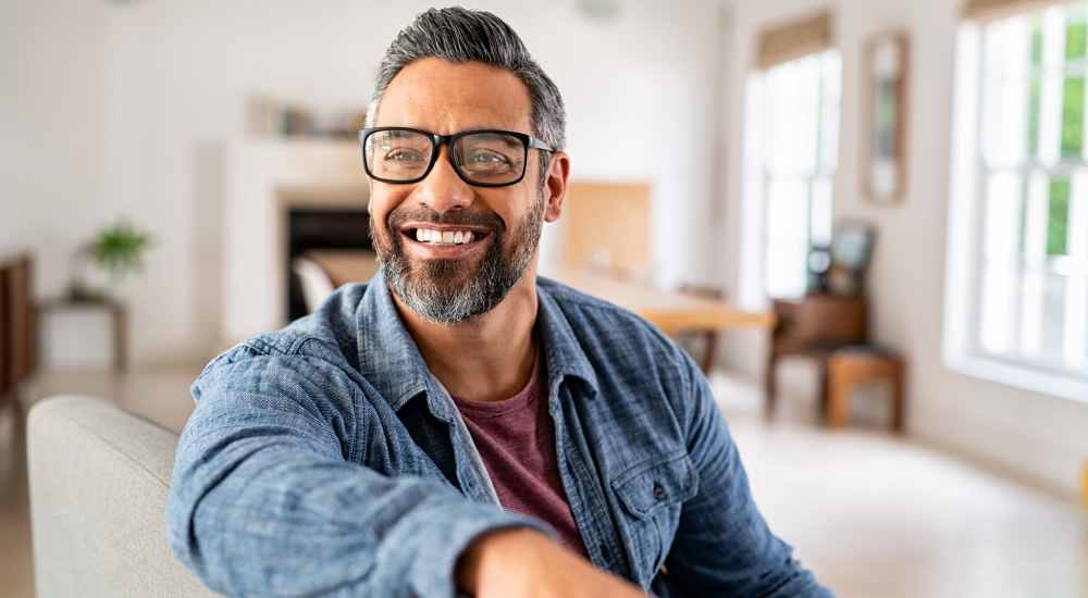 Resident peacefully sitting on a couch in his apartment at Cherokee Village in Dallas, Texas