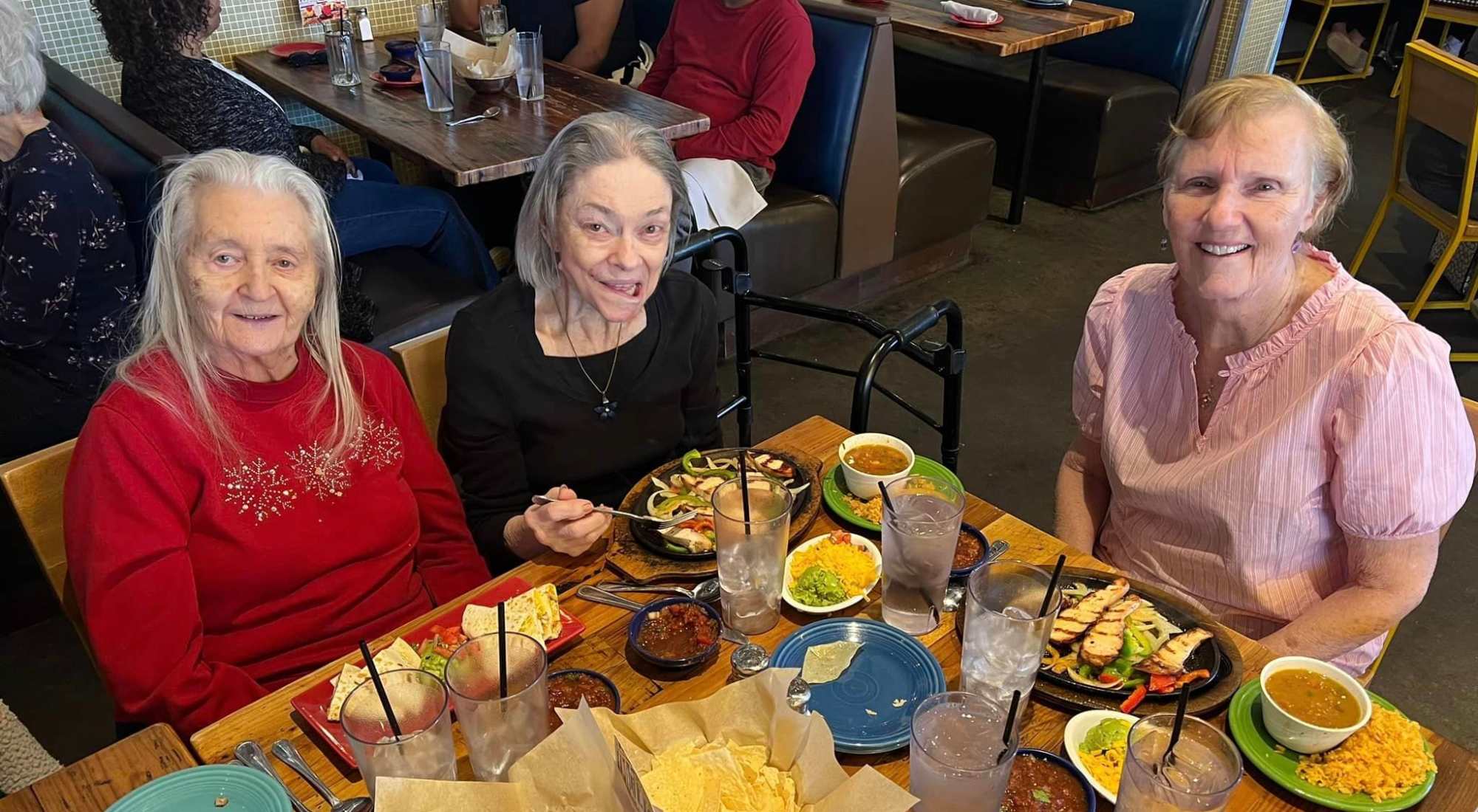 Three elderly women dining out at a Mexican restaurant, enjoying fajitas and conversation.