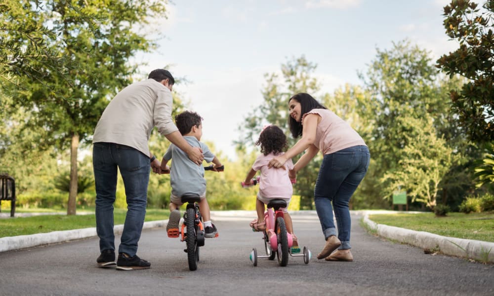 Family teaching their kids how to ride a bike at a park near Salishan Apartments in Citrus Heights, California