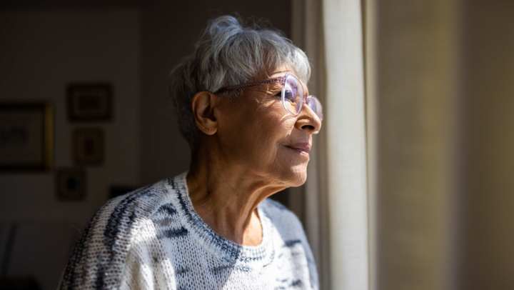 An elderly woman looking out the window