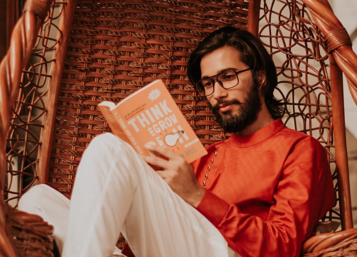 A person sitting in a wicker chair reading a book