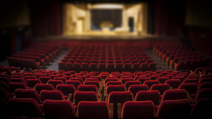 Red empty theater seats with a stage in the foreground