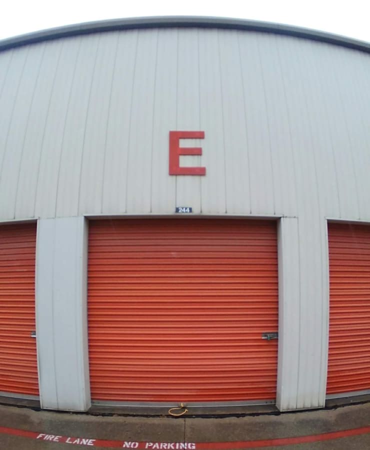 A row of outdoor units, with red doors closed, at StorageLand Rental Spaces in Arlington, Texas