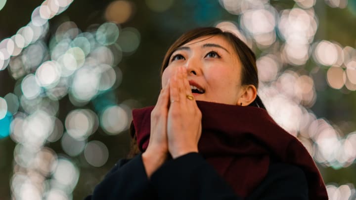A woman looking up in awe with blurred-out Christmas lights in the background