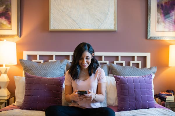Resident surfing the web on her phone in her new home at TerraLane at Canyon Trails in Goodyear, Arizona
