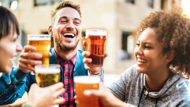 A group of smiling friends raise beer glasses in a toast