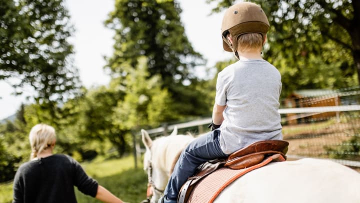 Young boy learning to ride a white horse | horseback riding in Gilbert