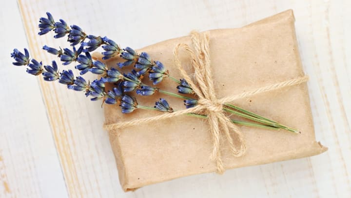 Gift box wrapped in parchment paper with dried lavender tucked into a twine bow.