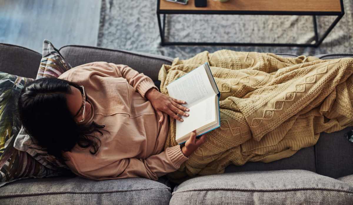 A resident reads a book on her sofa at Promenade Pointe, Norfolk, Virginia