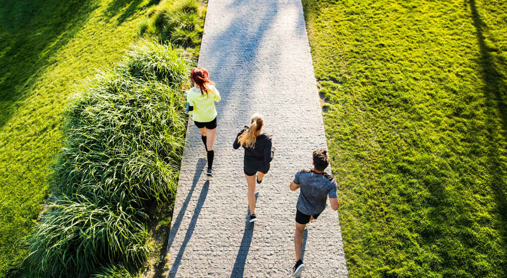 Three individuals jogging along a scenic path in a park near The Beacon in Fremont, California