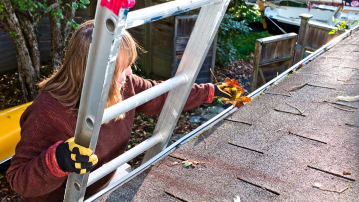 Woman climbing up a ladder to a roof. 