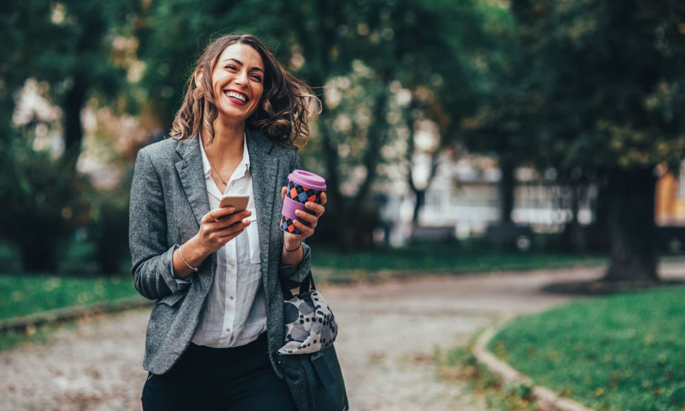 Resident walking to work with her morning coffee and laughing near Oaks 5th Street Crossing At City Center in Garland, Texas