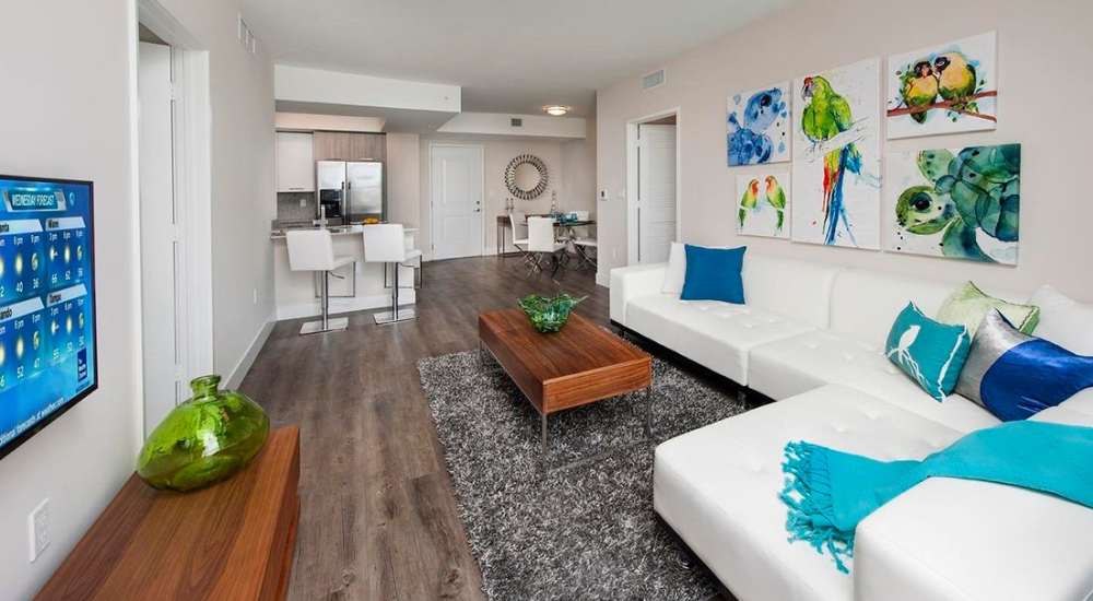 Living room with view to kitchen and hard wood flooring at Grove Station Tower in Miami, Florida