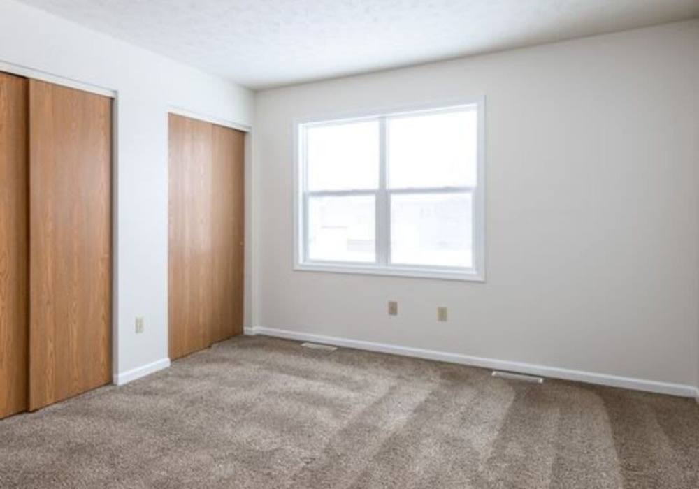 Model bedroom with carpet flooring at Unionville Station Townhomes in Hilton, New York