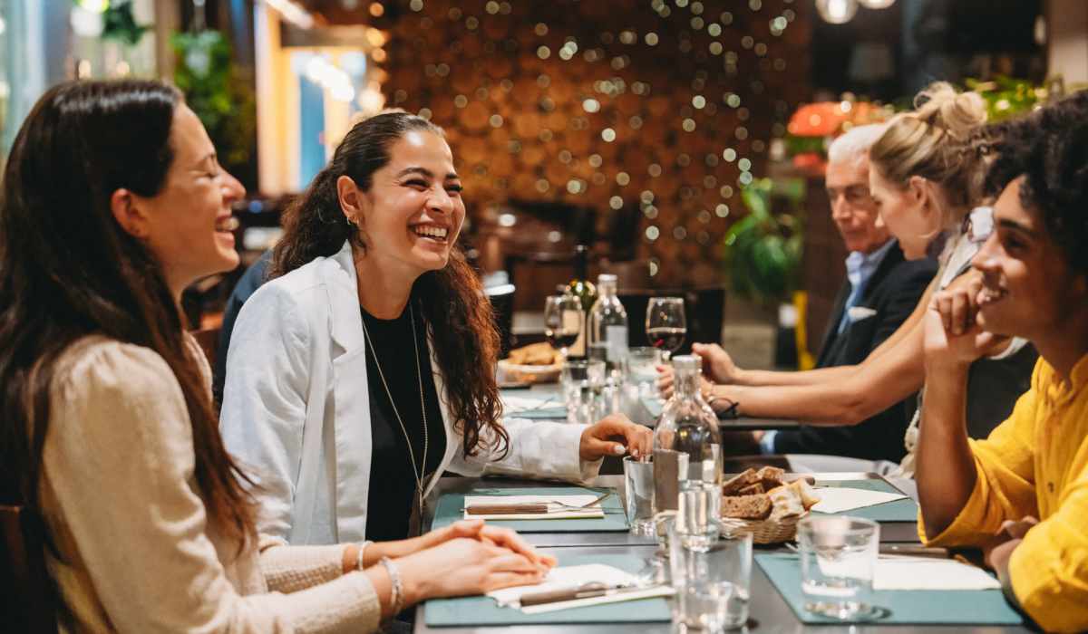 Group of friends enjoying dinner together, smiling and sharing conversation at a beautifully set table near Dutch Village Apartments in Baltimore, Maryland 