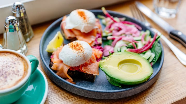 Poached eggs with salmon and half an avocado drizzled with olive oil on a plate