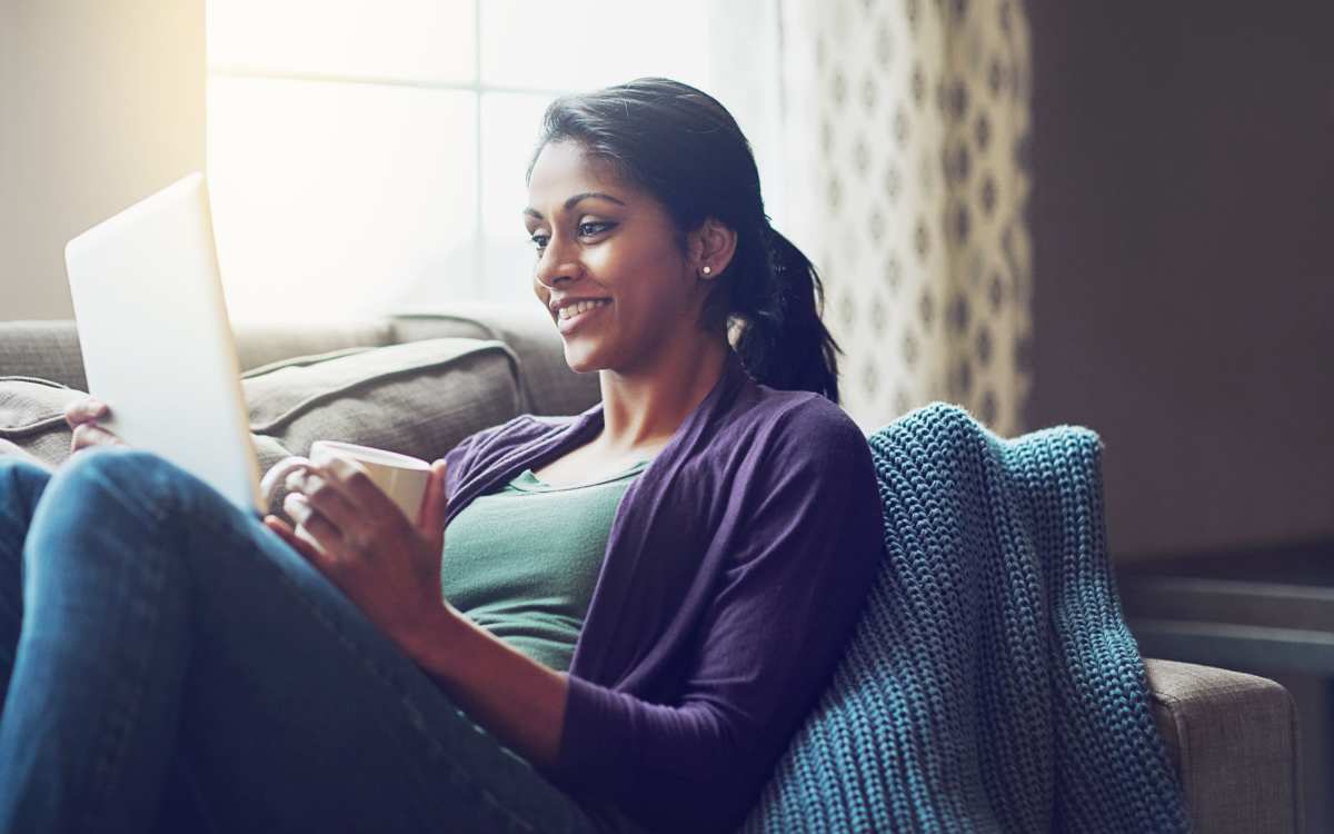 Woman smiling looking at her laptop while having a cup of coffee at Kirman Garden in Reno, Nevada