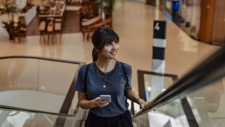 A smiling woman standing on an escalator in a Brunswick shopping center