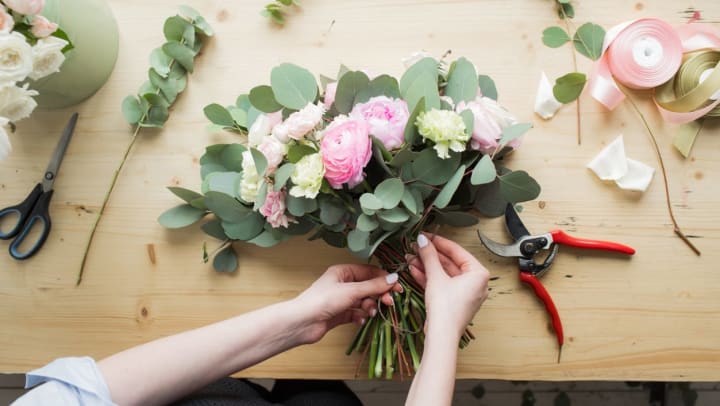 A florist tying together a bouquet of pink and white flowers | florists in Charlotte