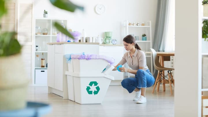 Woman sorting paper waste into the appropriate recycling bins in her apartment