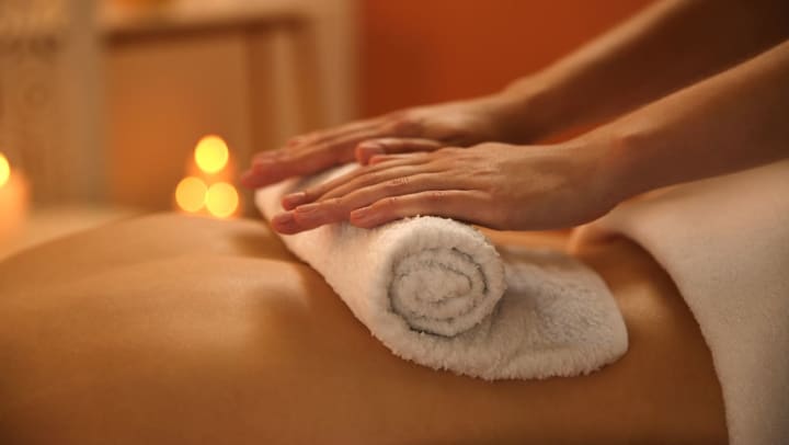  A masseuse rolls a hot towel on a person