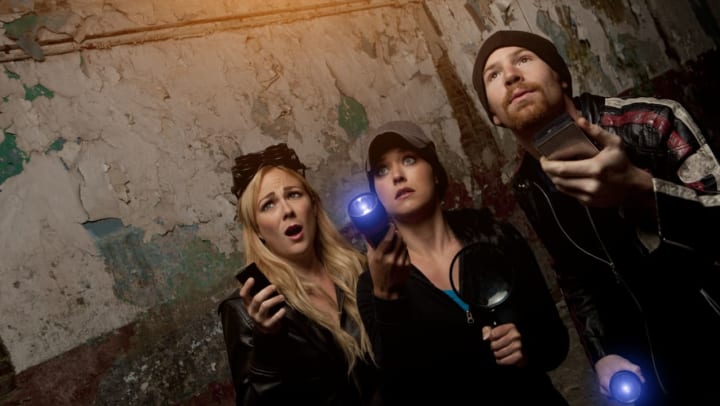 A group of scared friends with flashlights experiencing a haunted tour in Charlotte