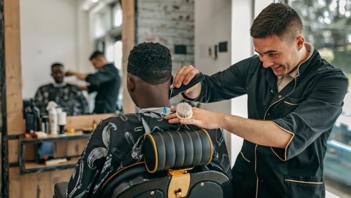 A man getting a haircut by a barber at a barber shop