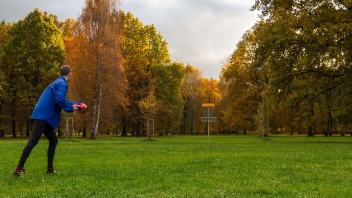 Young man playing disc golf in a field during autumn | activities in Katy
