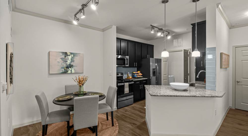 Apartment kitchen with stainless-steel appliances with dining area at The Loop in Conroe, Texas