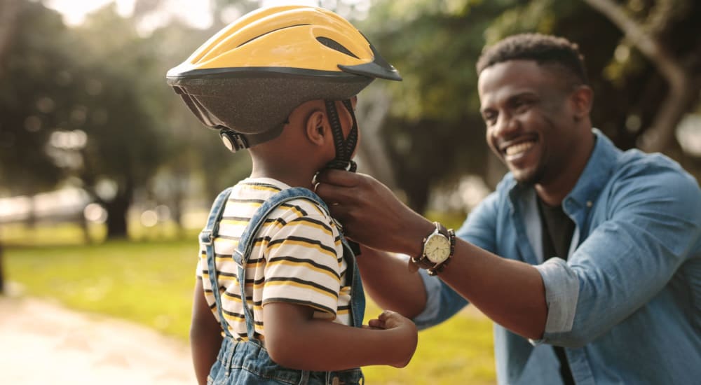 A resident putting a bike helmet on a child near The Legends on the Park in Eureka, Missouri