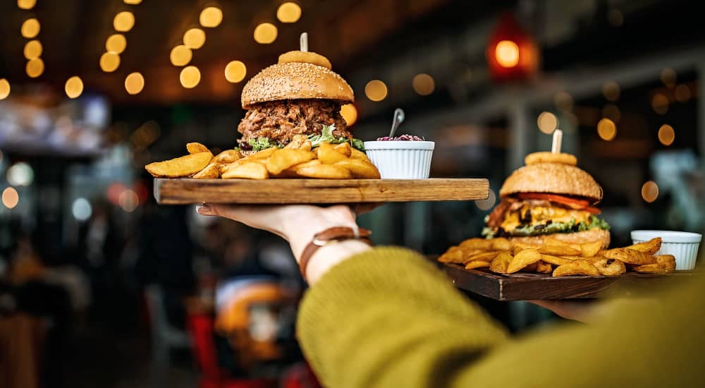 Image of two gourmet burgers with fries on wooden trays at a restaurant near Retreat at the Park in Burlington, North Carolina
