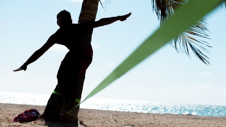 Resident slacklining between palm trees at the beach near The Hawthorne in Jacksonville, Florida