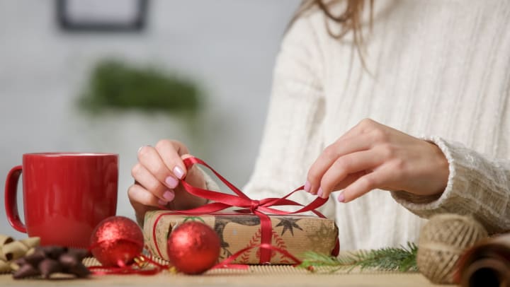 Woman wrapping Christmas presents with a cup of coffee