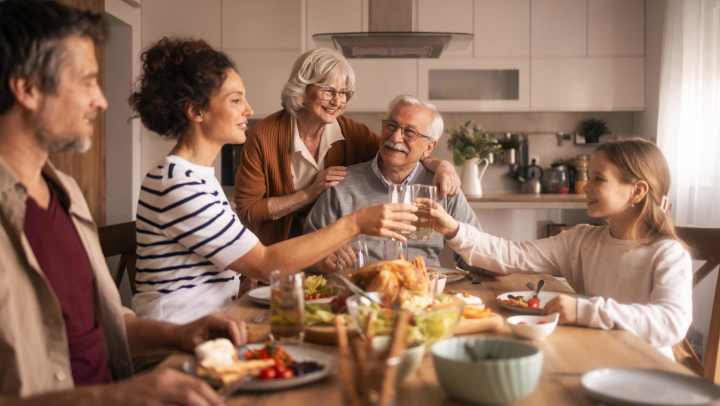 Group of people gathered around a dining table sharing a meal with dishes, drinks, and food spread across a well‑lit kitchen setting at {{location_name}} in {{location_city}}, {{location_state_name}}.