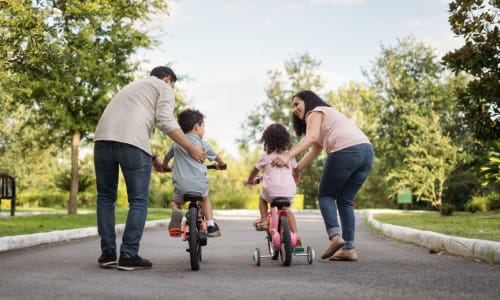 A family at the park teaching kids to ride a bike near Lakeshore Apartments in Concord, California