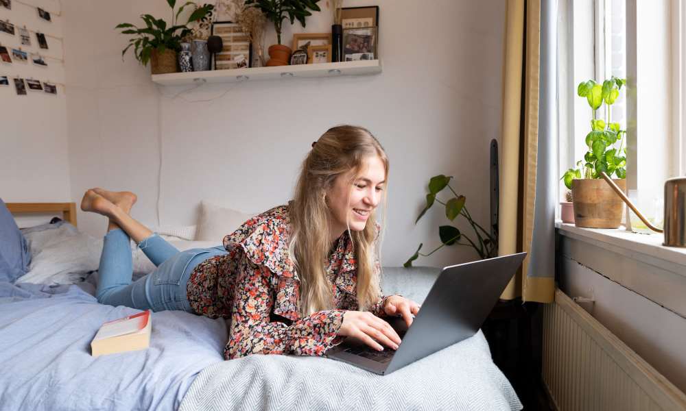 Resident using her laptop on the bed at University Orchard in Salisbury, Maryland