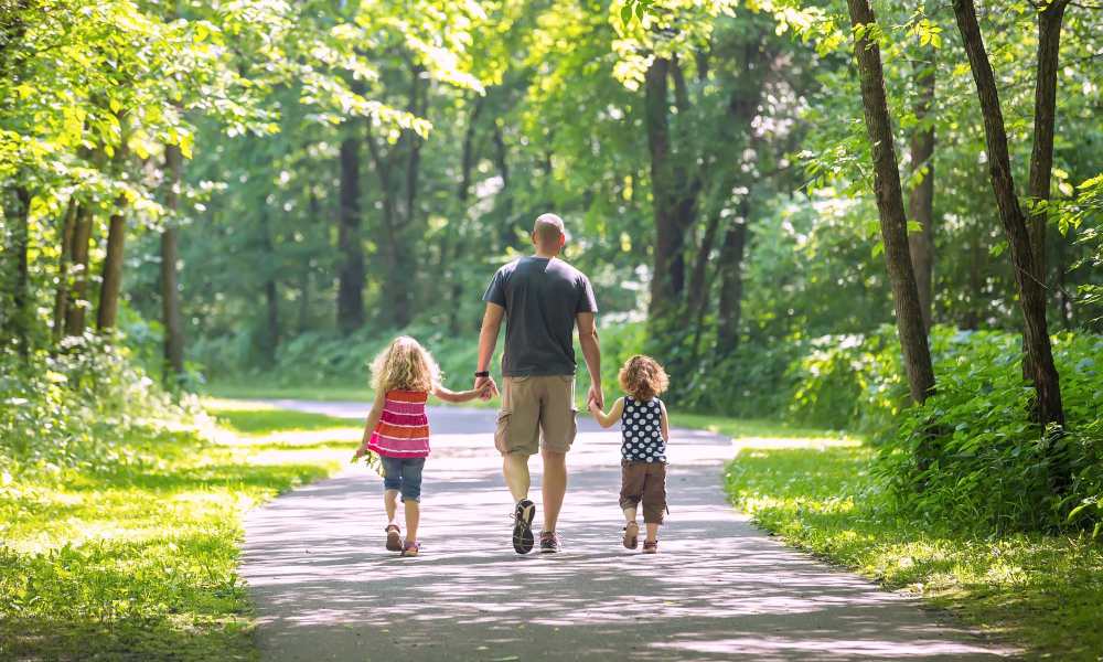 Resident walking with his children in park near The Courtyards At Fishing Creek in Chesapeake Beach, Maryland