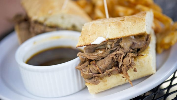 Prime rib on a baguette with a side of au jus and fries