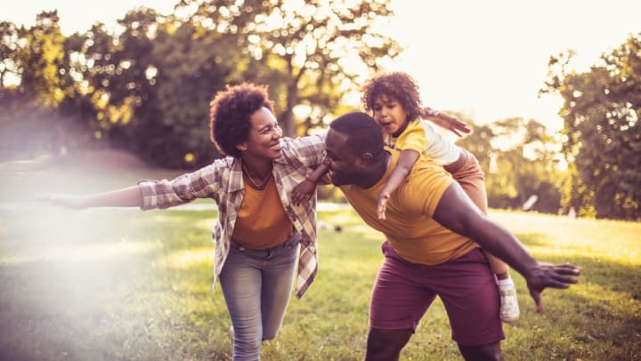 two adults playing with a kid in the park