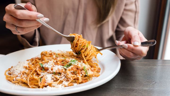 A close up of a woman twirling spaghetti on her fork while sitting at a table in a restaurant. | Spaghetti in Jacksonville