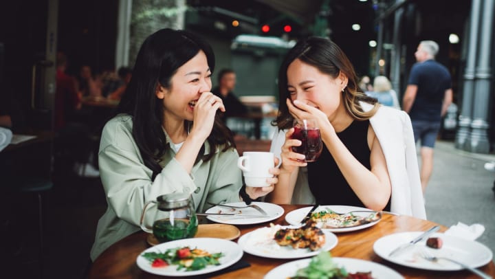 Two women laughing over a brunch gathering