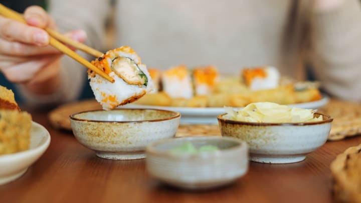 Close up of a woman eating sushi at a restaurant